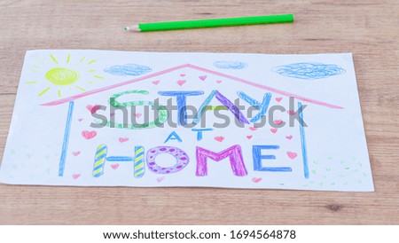 Quarantine at home during coronavirus pandemic. Kid drawing picture with words Stay at home on wooden table. Social media campaign for coronavirus prevention