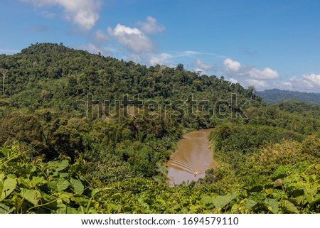 A native boat on the Millian River, a tributary of the Kinabatangan River, seen from the hill ridge at Penangah, Sabah, Malaysia