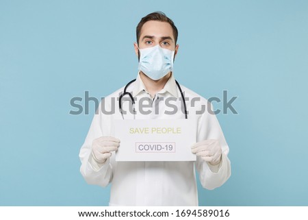 Male doctor man in medical gown face mask gloves isolated on blue background. Epidemic pandemic rapidly spreading coronavirus 2019-ncov sars covid-19 flu virus concept. Hold nameplate save people