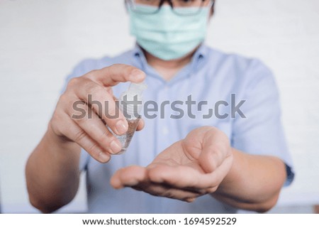 COVID-19, Close up man using bottle of antibacterial wash hand sanitizer gel dispenser, against Novel coronavirus (2019-nCoV) at home.  Home isolation and Healthcare concept.