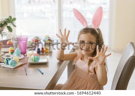 cute little child girl wearing bunny ears and decorate many different colors easter eggs