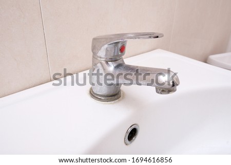 Dirty faucet with limescale, calcified water tap with lime scale on washbowl in bathroom, home cleaning concept.