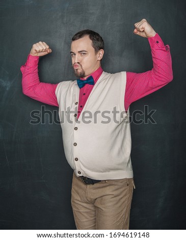 Funny nerd vintage style man flexing his muscle on blackboard background