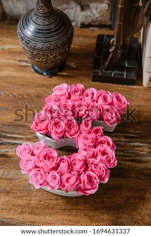Pink flowers in a plate in shape of number five. Lovely roses in vintage interior with clocks and books on wooden table