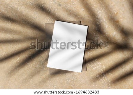 Summer stationery mock-up scene. Blank greeting card, craft envelope at sunset with date palm leaf shadow overlay. Golden marble table background. Flat lay, top view. Tropical vacation concept.