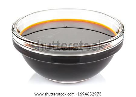 Soy sauce in a small transparent glass round bowl isolated on white background