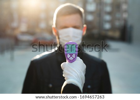 Operator check fever by digital thermometer visitor at information counter for scan and protect from coronavirus COVID-19 Royalty-Free Stock Photo #1694657263