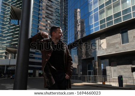 An elegant man in a sheepskin coat walks around the city