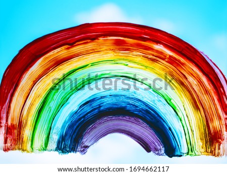 Close-up photo of painting rainbow on window. Rainbow painted with paints on glass is a symbol for many meanings.