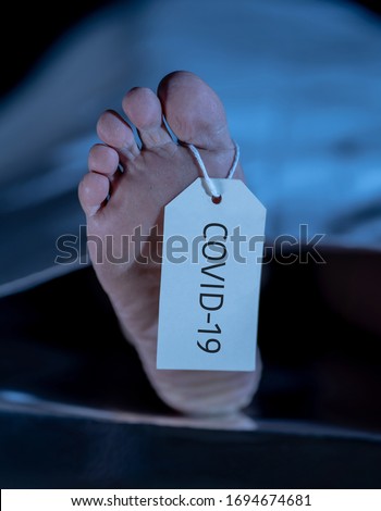 Global Health crisis. Image of feet with COVID-19 written on toe tag of a dead body victim of coronavirus infectious disease. Heath alert as virus death toll rises in countries around the world. Royalty-Free Stock Photo #1694674681