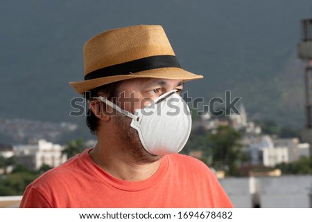 man wearing N-95 mask to protect himself from covid-19 on the balcony of his residence Royalty-Free Stock Photo #1694678482
