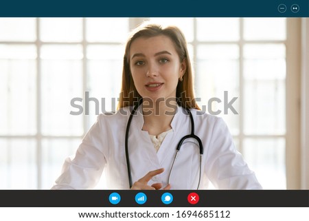 Head shot portrait female doctor wears white coat stethoscope on neck shares latest corona virus warnings by video call provide medical support to client via telecommunications app on pc or smartphone Royalty-Free Stock Photo #1694685112