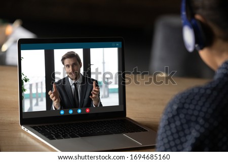 Woman wear headphones listen tutor during online class pc screen view over trainee shoulder. Colleague express opinion share ideas working together on project using video call, e-learn e-coach concept Royalty-Free Stock Photo #1694685160