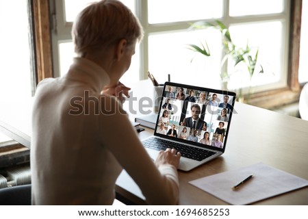 Rear view woman sit at desk learns new videoconference app online review, look at pc screen take part in group video call with corporate staff brainstorm distantly, study, work use modern tech concept Royalty-Free Stock Photo #1694685253