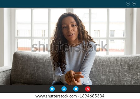 Computer screen view african woman sit on couch looking at webcam, share news with friend, applicant pass job interview by videoconference app, communicates with employer from home, video call concept Royalty-Free Stock Photo #1694685334