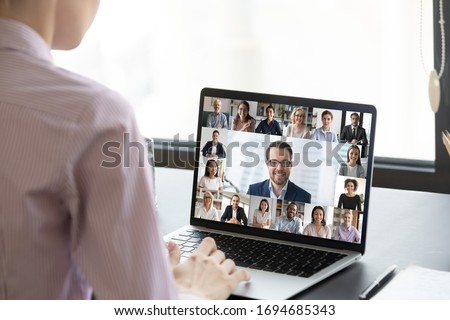 Multiracial people involved in group video call using modern tech videoconferencing application for study or business concept, view over businesswoman shoulder sitting at desk working with colleagues Royalty-Free Stock Photo #1694685343