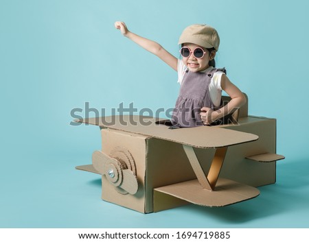 Asian little child girl playing with cardboard toy airplane handicraft isolated on blue background, Creative at home and dreams of flight concept Royalty-Free Stock Photo #1694719885