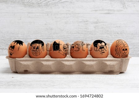 Social distancing and isolation during Easter concept depicted with funny faces drawn on eggs with copy space
