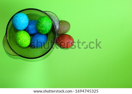 Lots of colored eggs on a green background. Marble eggs painted with speckles for Easter. in the plate