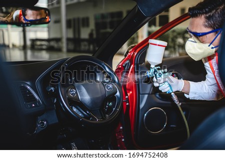 Free service for injection of the Covid-19 virus in the car. Picture of a mechanic wearing a protective mask and spraying the Covid-19 disinfectant in the car.