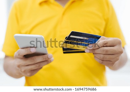the young man wears a yellow shirt holding blank white credit card mockup. Plain creditcard mock up template with electronic chip holding arm. Plastic bank-card display front design. Business branding