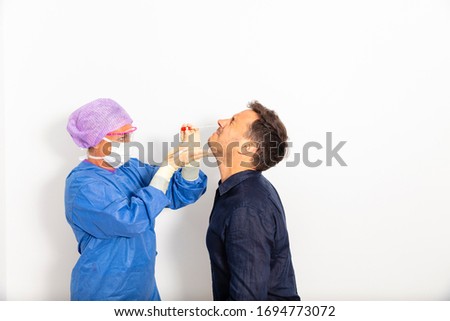 A doctor in a protective suit taking a nasal swab from a person to test for possible coronavirus infection Royalty-Free Stock Photo #1694773072