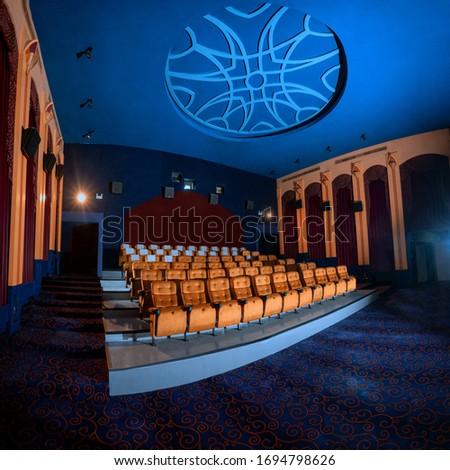 Large cinema theater interior with seat rows for audience to sit in movie theater premiere by cinematograph projector. The cinema theater is decorated in classical for luxury feel of movie watching. Royalty-Free Stock Photo #1694798626