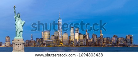 Panorama statue of liberty Landmark of New York with aerial view of New York city Lower Manhattan skyscraper skyline building cityscape at dusk from New Jersey in background. 