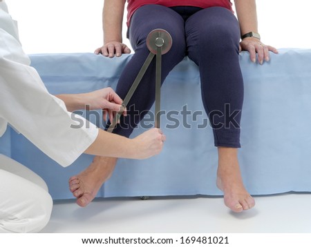 Physiotherapist measuring active range of motion of older patient's lower limb using manual goniometer