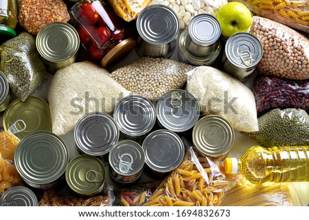 Set of raw cereals, grains, pasta and canned food on the table. Royalty-Free Stock Photo #1694832673