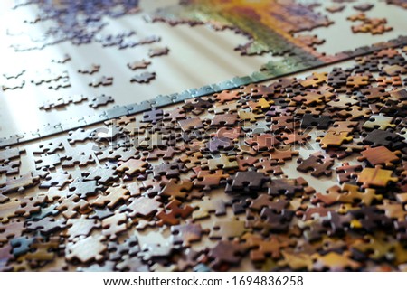 Scattered jigsaw puzzle pieces in natural colors. Lying on table. Concept of putting together disconnect elements.