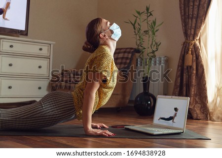 Sporty young woman taking yoga lessons online and practice at home while being quarantine. Concept of healthy lifestyle, wellness, being safe while coronavirus pandemic, looking for new hobby.