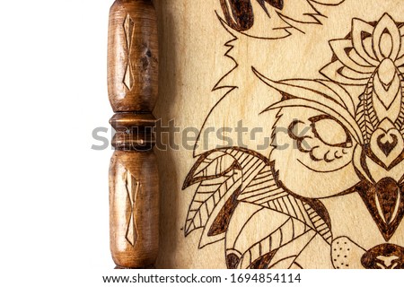 Part of wooden picture with the image of a wolf made using the technique of pyrography and decorated with a carved frame. On white background
