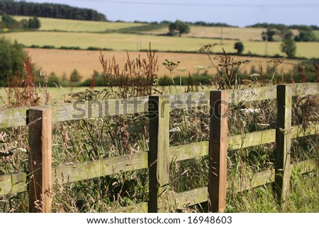 Along the wooden fence line the countryside in the background