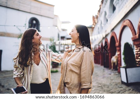Excited toothy female fellows 20 years old satisfied with random meeting in city downtown, happy Caucasian women laughing rejoicing and socialising during friendly walking at urban streets Royalty-Free Stock Photo #1694863066