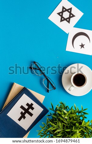 Interfaith dialogue concept. World religions symbols near book on blue background top view copy space