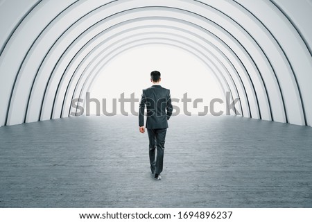 Businessman walking in minimalistic illuminated corridor interior and creative lighting. Art and design concept. Mock up,