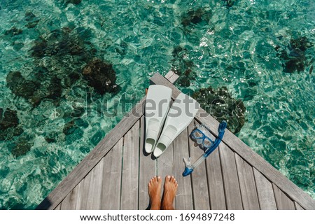 Beach vacation snorkel girl snorkeling with mask and fins. Equipment for snorkeling. Woman legs on wooden pier with snorkeling equipment Royalty-Free Stock Photo #1694897248