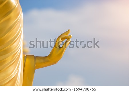Gold buddha hand. Big buddha hand sculpture with blue sky in background. Buddha hand statue with sun light. Close up hand. Royalty-Free Stock Photo #1694908765