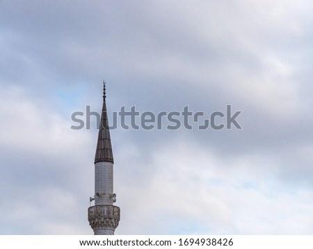 Minaret of a Muslim mosque on the background of the cloudy sky. minaret aspiring to heaven. Royalty-Free Stock Photo #1694938426