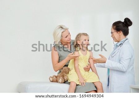 Pediatrician talking to little girl and her mother and explaining prescription