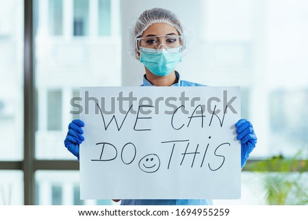 Healthcare worker holding placard with supportive 'we can do this' message while standing in the hospital.  Royalty-Free Stock Photo #1694955259