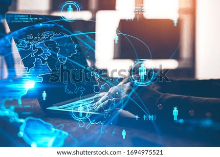 Hands of businesswoman typing on laptop in blurry office with double exposure of blurry social network interface. Concept of HR. Toned image