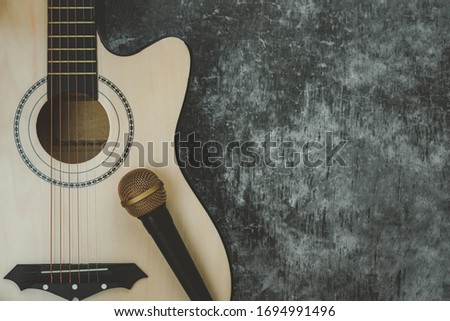 Table top view of music instrument tools concept background.Flat lay of sign to sing for musician or party equipment.Guitar with microphone on modern grey cement.copy space for creative design. 
