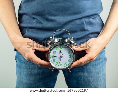 Man over forty holds an alarm clock in his hands, prostate prevention, pain Royalty-Free Stock Photo #1695002197