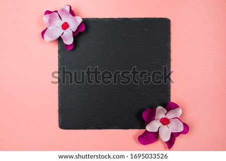Black square with purple and white flowers on a pastel pink background