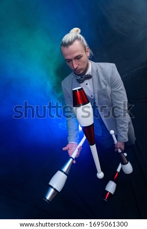 Man wearing formal suit juggling with clubs. Management, control and success