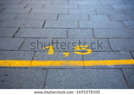 Yellow marking on street in order to guide social distancing due to coronavirus or covid-19 pandemic. Yellow marking indicating how much distance people should keep to be safe. 1.5 meters, lockdown Royalty-Free Stock Photo #1695078100