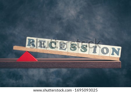 Recession spelled in letters on seesaw againstd ark background