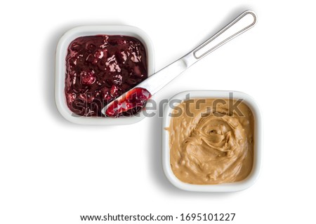 Peanut butter and strawberry jelly in bowls isolated on white background with strawberry jam spreading knife Royalty-Free Stock Photo #1695101227